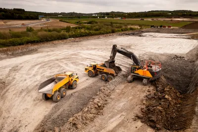 Aerial view of construction site with yellow dump truck and heavy machinery.
