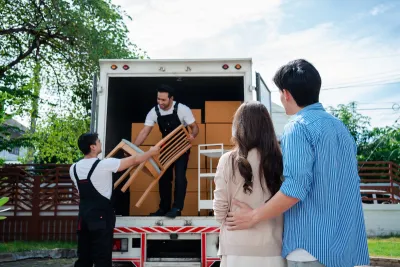 Couple watches as two movers loan furniture into back of box truck.