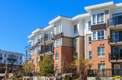 Four-story modern apartment complex with white stucco and red brick.