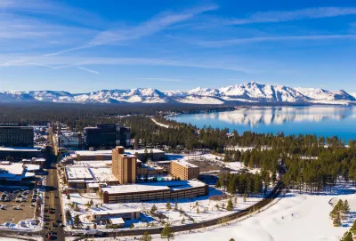 Aerial view of snowy town of Stateline, Nevada on shore of Lake tahoe with mountains in background.