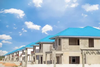 Row of concrete two-story homes with blue tile roofs under construction.