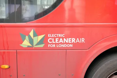 Close-up of geometric green leaf logo and "Electric Cleaner Air for London" white text on side of red London bus.