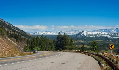 Curve in mountain highway along Teton Pass with snowy Wyoming mountains in background.