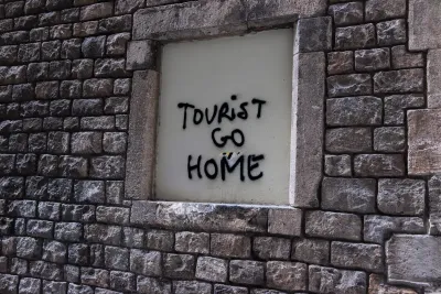 Spray painted words "Tourist Go Home" on wall in Barcelona illustrate locals' frustration with overtourism.