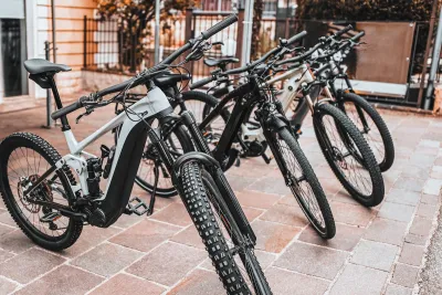 Black e-bikes sitting on a sidewalk outdoors.