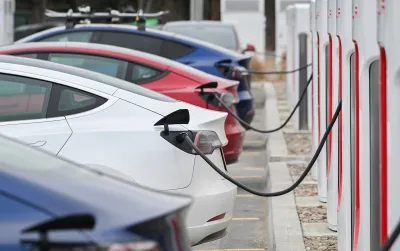 Close-up of four Tesla sedans parked and plugged in at charging station.