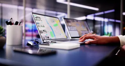 Close-up of hand on laptop keyboard with real estate listings and map pulled up on screen.
