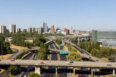 Aerial view of highway overpasses with Portland, Oregon skyline in background.