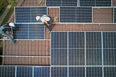 Bird's eye view of workers installing solar panels on rooftop.