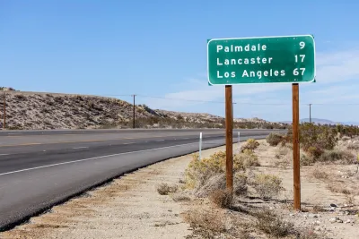 Green highway sign with white text with distances for Palmdale, Lancaster, and Los Angeles, California.