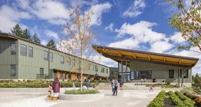 Green u-shaped school building with slanted roof and courtyard in the middle