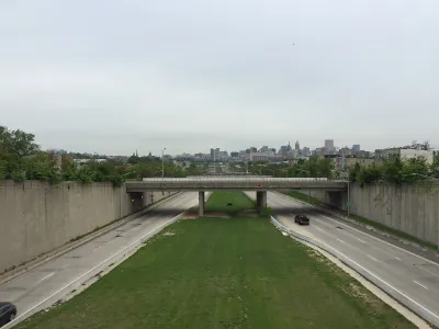 View from overpass of highway with one truck and green median with Baltimore city in the background