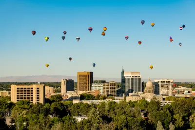 Hot air balloons rise over Downtown Boise with the State Capitol building visible amidst the high rises.