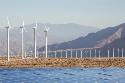 Wind turbines and solar panels against a backdrop of mountains in the Mojave Desert near Palm Springs, California