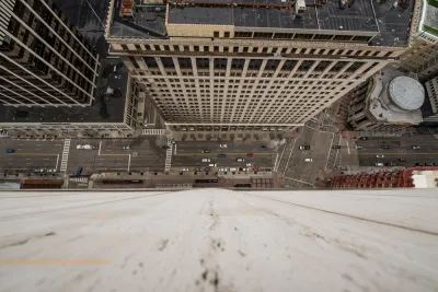 A busy urban street is seen from the vantage point offered by looking straight down from the top of a high-rise.