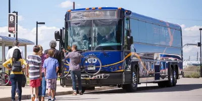 Passengers boarding a blue Flatiron Flyer BRT bus in Denver, Colorado.