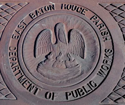 Close-up of metal manhole cover with pelican logo and 'East Baton Rouge Parish Department of Public Works.'