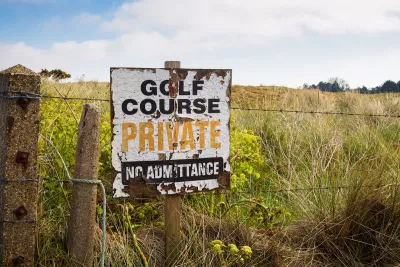 A derelict sign on a barbed wire fence reads “Golf Course, Private, No Admittance.”