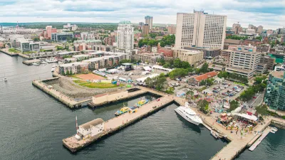 Aerial view of Halifax Waterfront with people milling around on docks among yellow umbrellas and business patios.