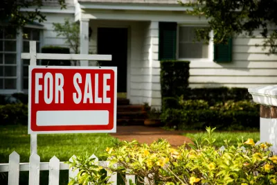 White clapboard house with For Sale sign in front yard