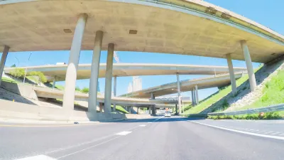 An image taken from the point of view of a driver on a mostly empty freeway, with large overpasses overhead.