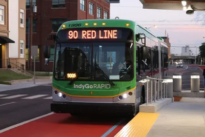 Green rapid transit bus pulled into station in dedicated lane.
