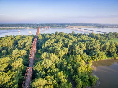 Two bridges cross the Mississippi Rivera midst thick vegetation and few other signs of human intervention.