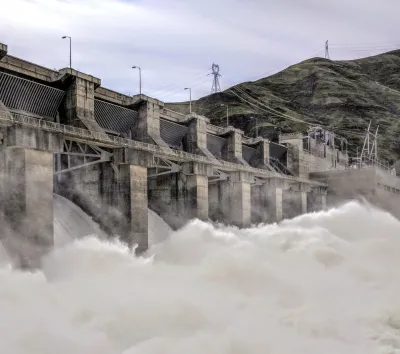 Water rushes over a spillway at a large concrete dam.