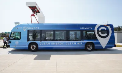 Blue electric MCTS bus sits at a charging station