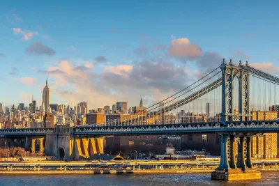A view of the Manhattan Bridge with the Empire State Building in the distance.