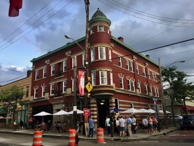 Brick three-story building with restaurant patio umbrellas outside ground floor in Little Italy neighborhood in Cleveland, Ohio.