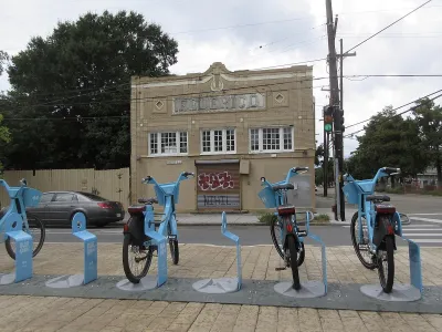 Row of blue Blue Bikes bike share bikes at docked station on sidewalk in New Orleans, Louisiana.