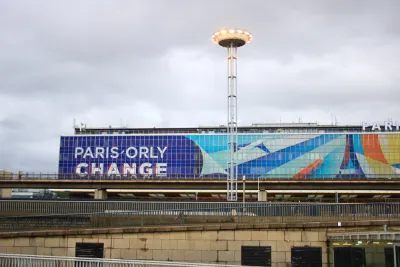 The exterior of a terminal at Orly Airport in France, with a large graphic that reads “Orly Change.”