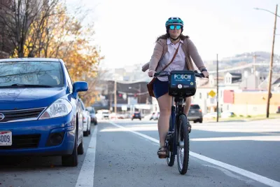 Woman wearing helmet riding POGOH bike share bike in bike lane in Pittsburgh, PA.