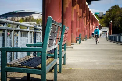 A single bike rider wearing a mask rides along a waterfront in Portland, Oregon.