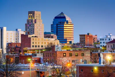 An image of the Raleigh skyline, with older residential buildings in the foreground and taller commercial buildings in the background.