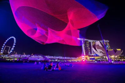 Pink light art installation above public plaza in Singapore by Janet Echelman.