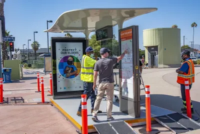 Two men looking at wayfinding sign on prototype bus shelter in North Hollywood, California.