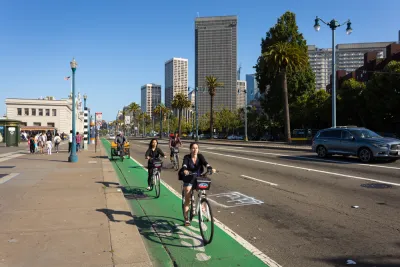 A group of cyclists rides on a green painted bike line on the Embarcadero in Sa Francisco.