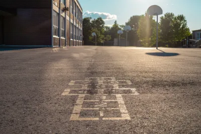 Hopscotch squares on concrete schoolyard with basketball hoop in background