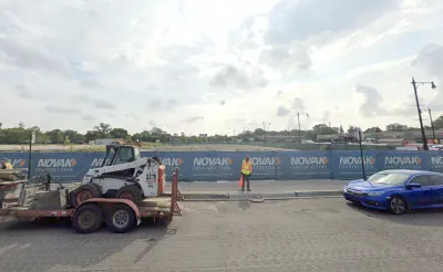 Google Street View of empty construction site with blue construction fence