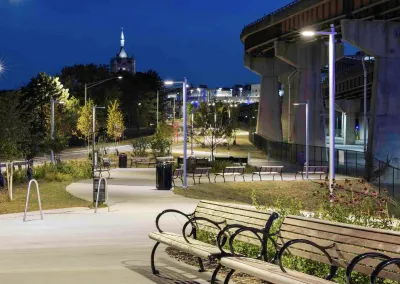 Benches along lit paved bike trail adjacent to freeway overpass in Albany, New York