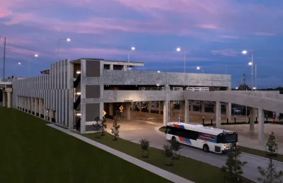 View of Westpark/Lower Uptown transit center in Houston with bus exiting three-story garage vuilding and purple sunset sky in background