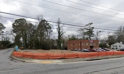 Vacant corner lot in Atlanta, Georgia surrounded with low orange plastic construction fencing.