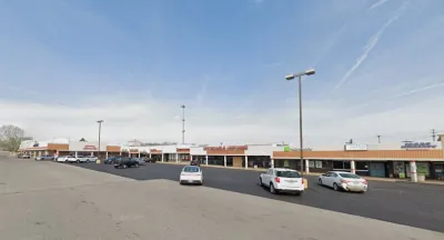 Google Maps view of one-story shopping center with large parking lot.