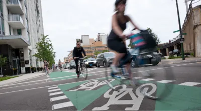 Cyclists riding on green painted bike lane protected by flexible post delineators in Chicago, Illinois.