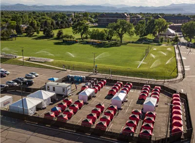 Ice fishing tents surrounded by fence in Safe Outdoor Space for unhoused people in parking lot in Denver, Colorado.