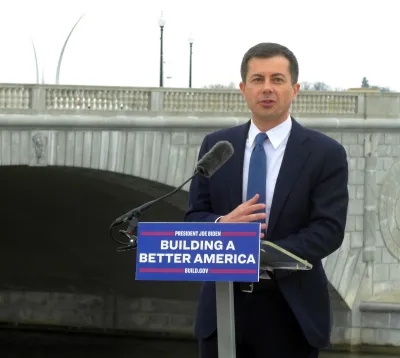 U.S> Department of Transportation Secretary Pete Buttigieg delivers a speech in front of a bridge in Washington, D.C. The podium where he stands has a sign that reads: "Building a Better America."