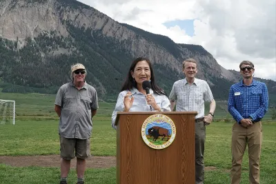 Sec. Deb Haaland speaking at dais outdoors with Colorado mountains in background and three officials standing behind her announcing protection of Thompson Divide.