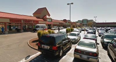 A typical American shopping center, with a thrift store at one end and a parking lot full of cars.
